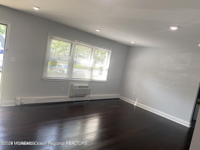 empty room with a wall mounted AC and dark hardwood / wood-style flooring