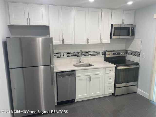 kitchen featuring appliances with stainless steel finishes, white cabinets, sink, and backsplash