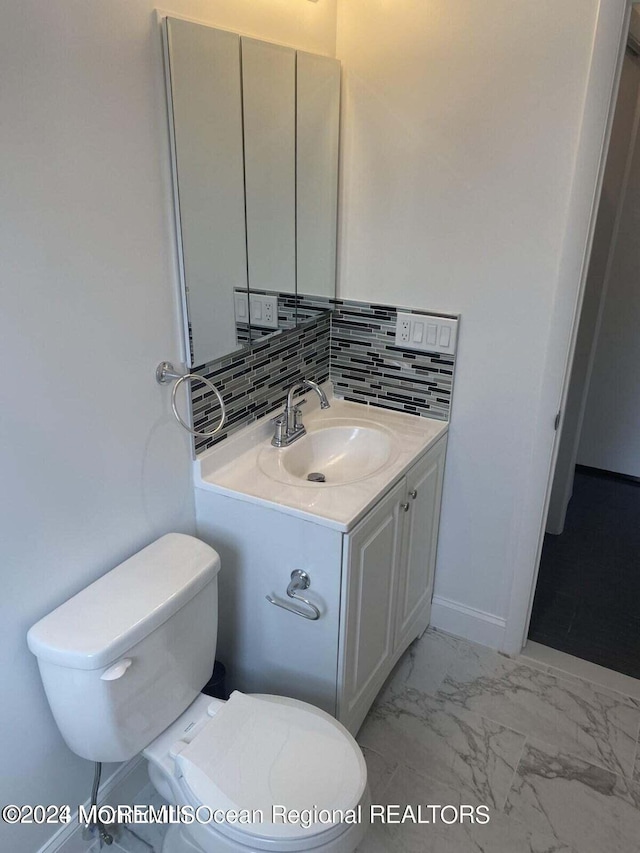 bathroom with vanity, toilet, and tasteful backsplash