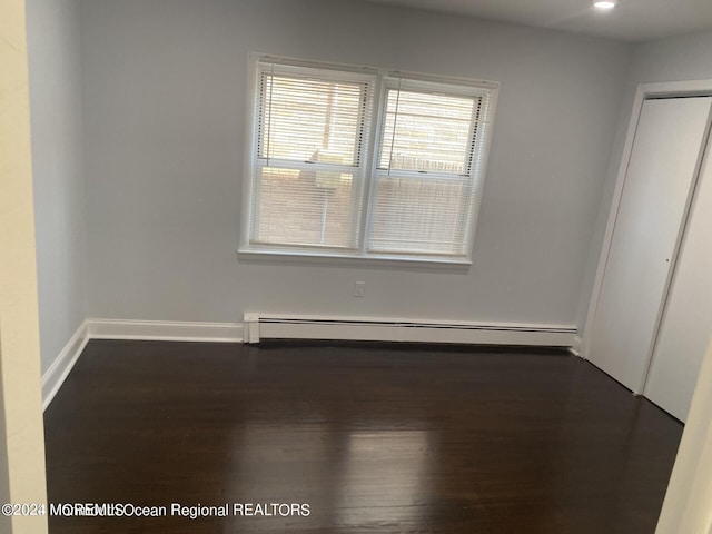 interior space with dark wood-type flooring, a closet, and baseboard heating