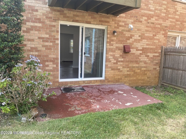 view of exterior entry with a patio and a yard