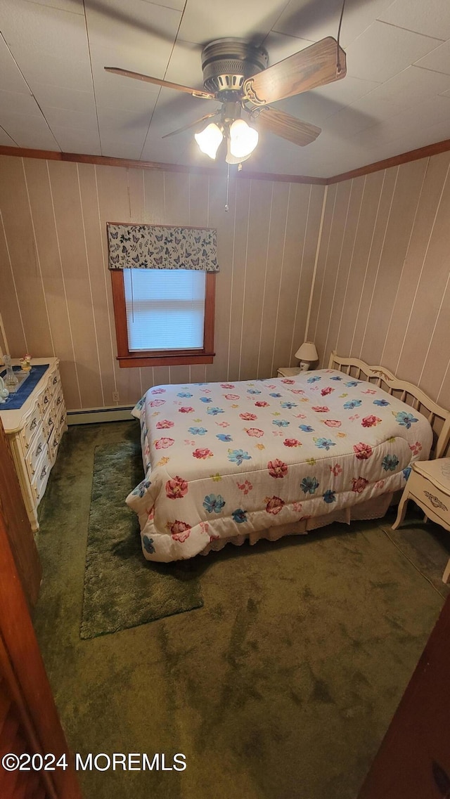 carpeted bedroom with crown molding, wood walls, baseboard heating, and ceiling fan