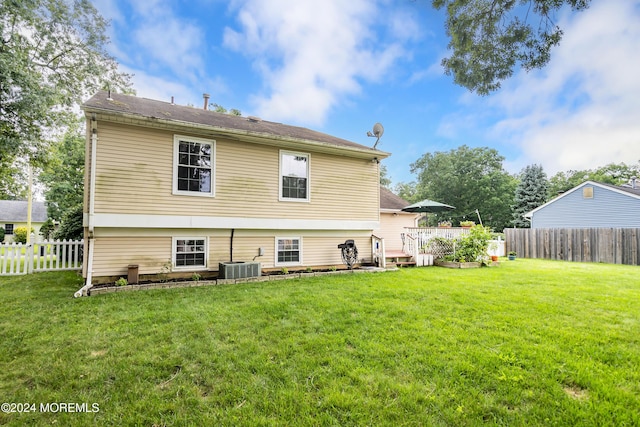 back of house with cooling unit, a wooden deck, and a lawn