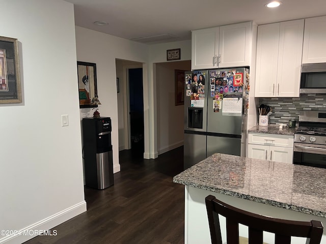 kitchen with decorative backsplash, light stone counters, stainless steel appliances, white cabinets, and dark hardwood / wood-style floors