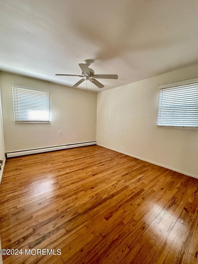 unfurnished room with ceiling fan, a baseboard radiator, and light hardwood / wood-style flooring