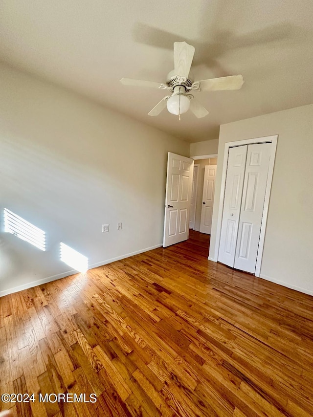 unfurnished bedroom featuring hardwood / wood-style floors, a closet, and ceiling fan