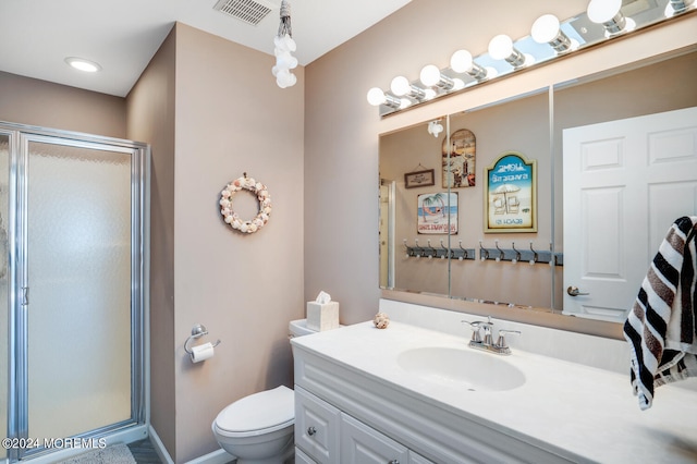 bathroom with vanity, a shower with shower door, and toilet