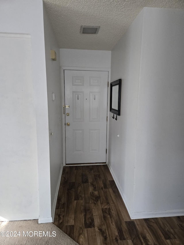 corridor with a textured ceiling and dark hardwood / wood-style flooring