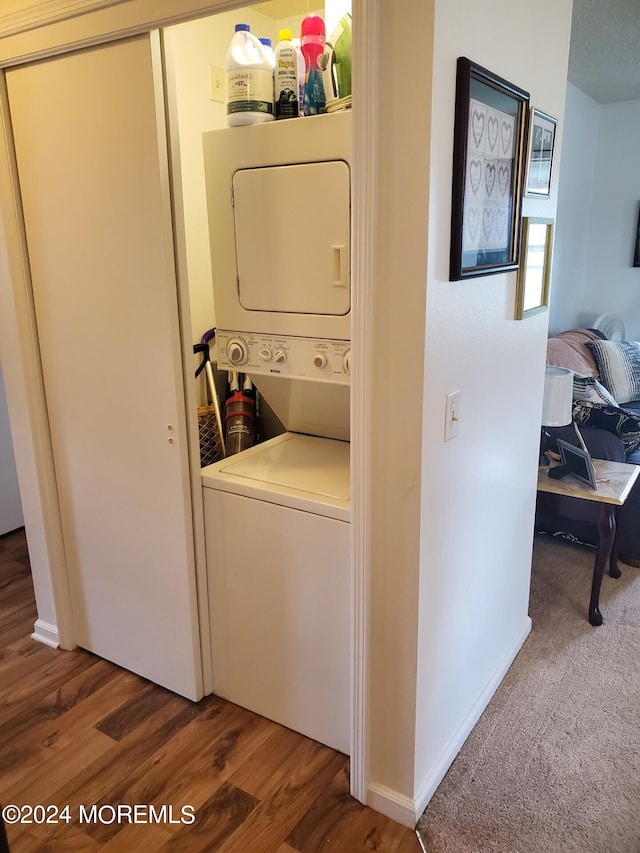 washroom featuring dark wood-type flooring and stacked washer / dryer