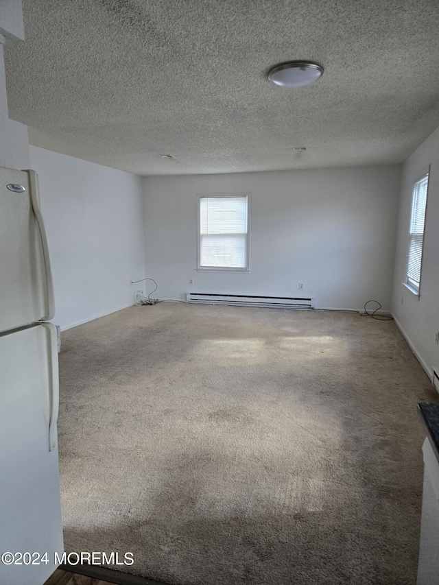 empty room featuring a textured ceiling, a baseboard heating unit, and carpet floors