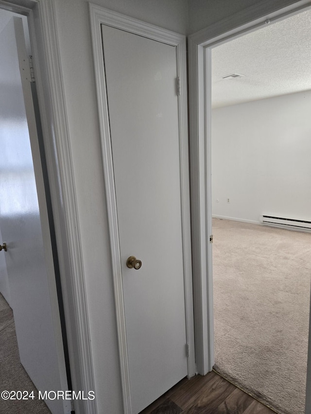 interior space featuring baseboard heating, dark wood-type flooring, and a textured ceiling