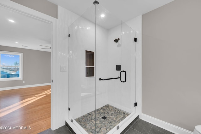 bathroom featuring ceiling fan, wood-type flooring, and walk in shower