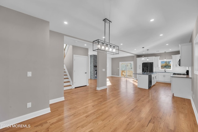 kitchen featuring black fridge, a kitchen island, decorative light fixtures, light hardwood / wood-style flooring, and white cabinetry