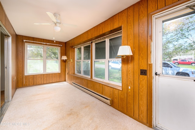 unfurnished sunroom featuring ceiling fan, a baseboard heating unit, and a wealth of natural light