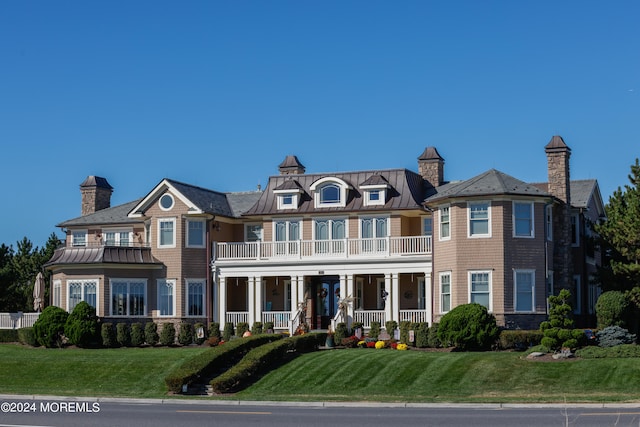 view of front facade with a balcony, covered porch, and a front lawn