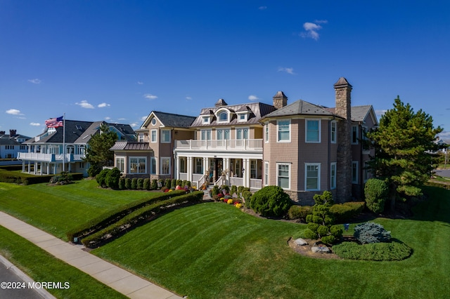 view of front of house featuring a front lawn and a balcony