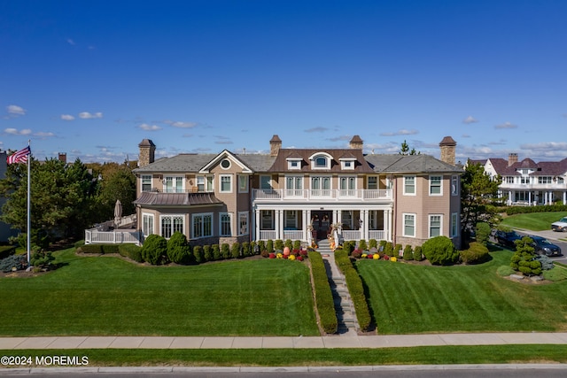 view of front of house featuring a balcony and a front lawn