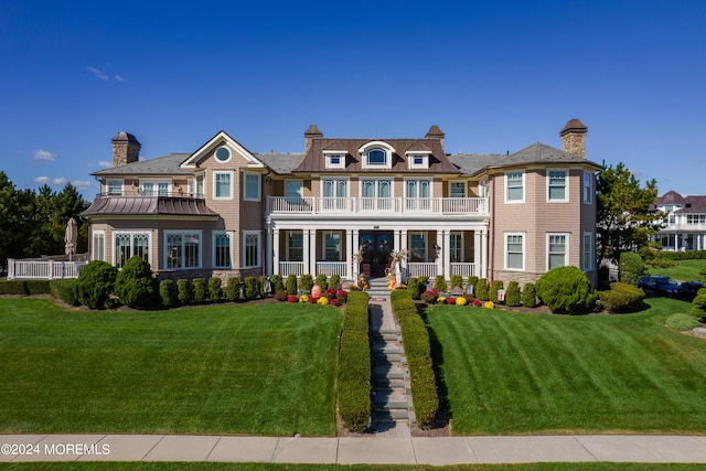 view of front facade featuring a balcony, covered porch, and a front lawn