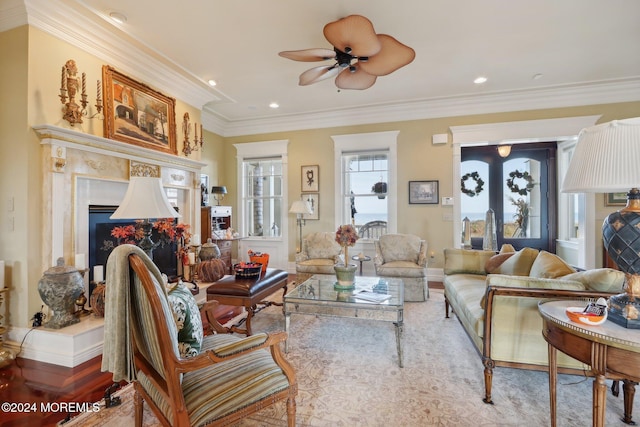 living room with a high end fireplace, crown molding, and ceiling fan