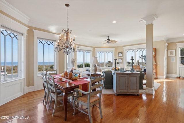 dining area featuring ornamental molding, light hardwood / wood-style flooring, ornate columns, and ceiling fan with notable chandelier