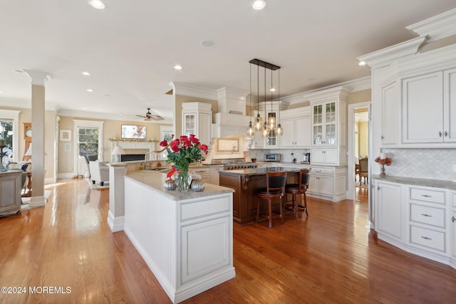 kitchen featuring tasteful backsplash, hanging light fixtures, wood-type flooring, a kitchen bar, and a center island