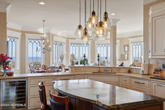 kitchen with decorative backsplash, hanging light fixtures, beverage cooler, a kitchen island, and sink