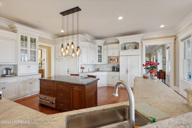 kitchen featuring backsplash, a center island, hanging light fixtures, white cabinetry, and paneled refrigerator