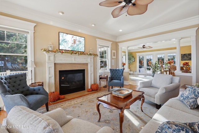 living room with crown molding, a healthy amount of sunlight, and decorative columns