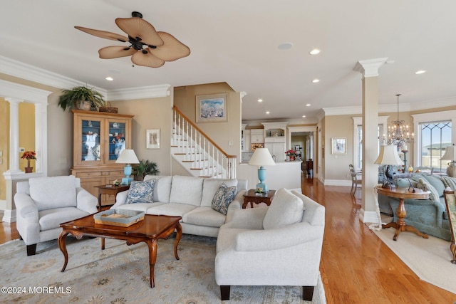 living room featuring ornamental molding, decorative columns, ceiling fan with notable chandelier, and light hardwood / wood-style floors