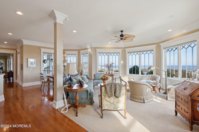 living room featuring decorative columns, crown molding, hardwood / wood-style flooring, and ceiling fan