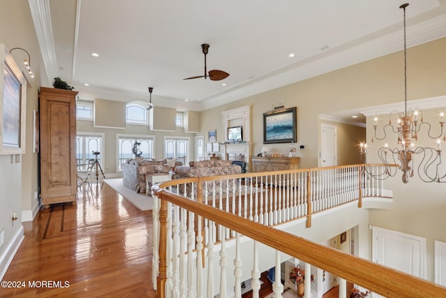 corridor with ornamental molding, an inviting chandelier, hardwood / wood-style floors, and a towering ceiling