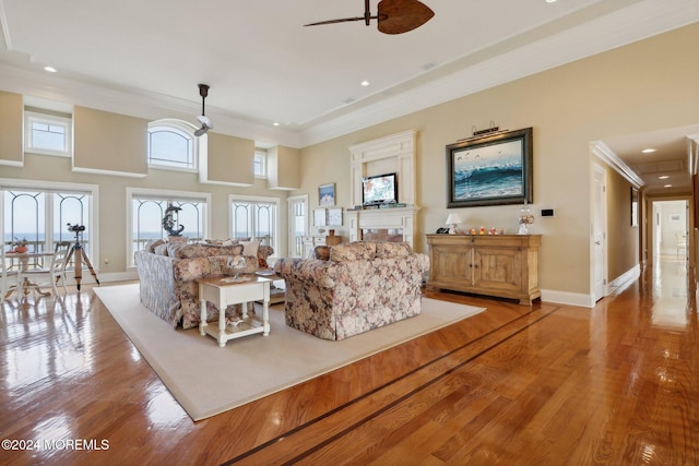 living room featuring hardwood / wood-style floors, crown molding, a towering ceiling, and ceiling fan