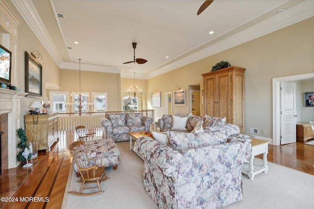 living room with wood-type flooring, ornamental molding, plenty of natural light, and ceiling fan with notable chandelier