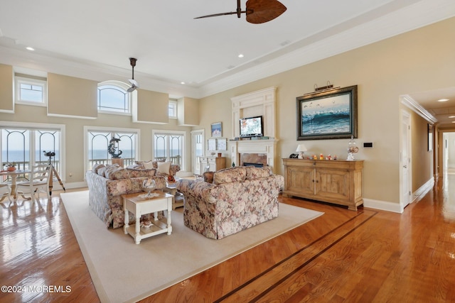 living room featuring a high ceiling, crown molding, light hardwood / wood-style floors, and ceiling fan