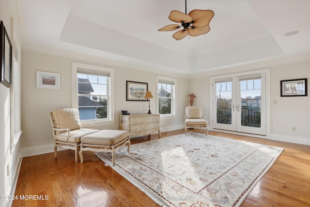 sitting room with french doors, ceiling fan, wood-type flooring, and a raised ceiling