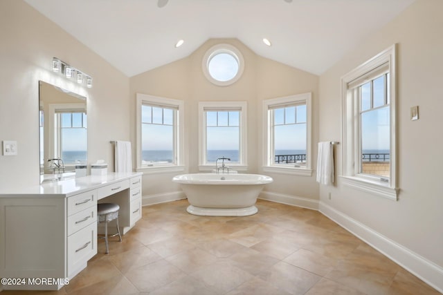 bathroom featuring a bathtub, tile patterned floors, vaulted ceiling, and vanity