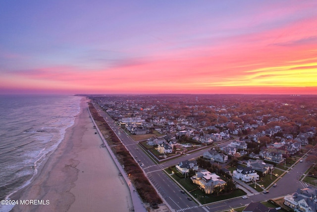 aerial view at dusk with a water view and a beach view