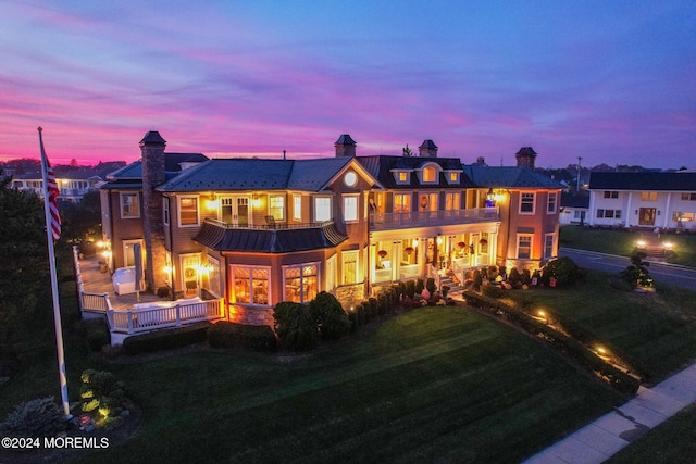 1805 Ocean Ave, Spring Lake, NJ 07762 - back of property at dusk with a balcony, a standing seam roof, a yard, and metal roof