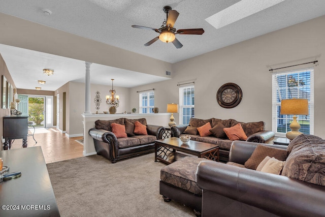 living room featuring ornate columns, a textured ceiling, light wood-type flooring, and ceiling fan with notable chandelier