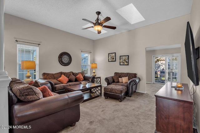 living room featuring light carpet, a textured ceiling, a skylight, and ceiling fan