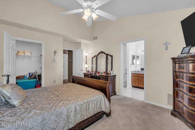 carpeted bedroom with a closet, ceiling fan, ensuite bathroom, and a walk in closet