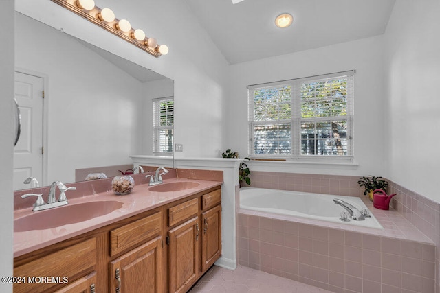 bathroom with vanity, lofted ceiling, and tiled bath