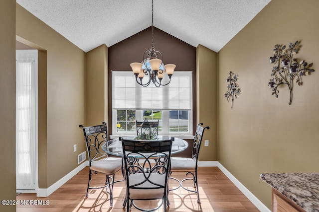 dining space featuring lofted ceiling, hardwood / wood-style floors, a textured ceiling, and an inviting chandelier