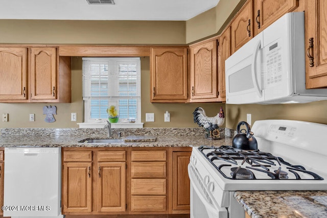 kitchen with light stone counters, sink, and white appliances