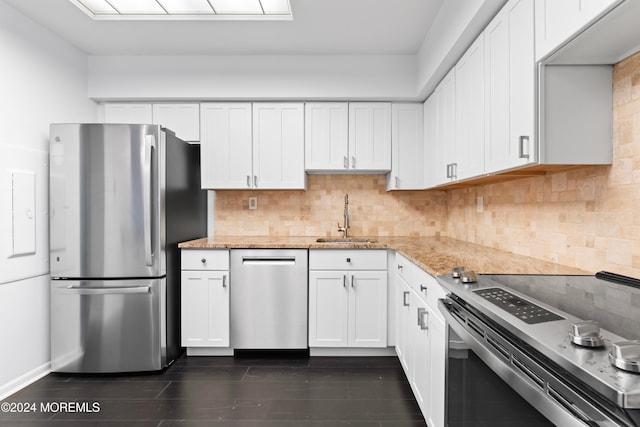 kitchen with light stone counters, appliances with stainless steel finishes, dark hardwood / wood-style floors, sink, and white cabinets