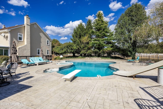 view of swimming pool featuring a patio, an in ground hot tub, and a diving board