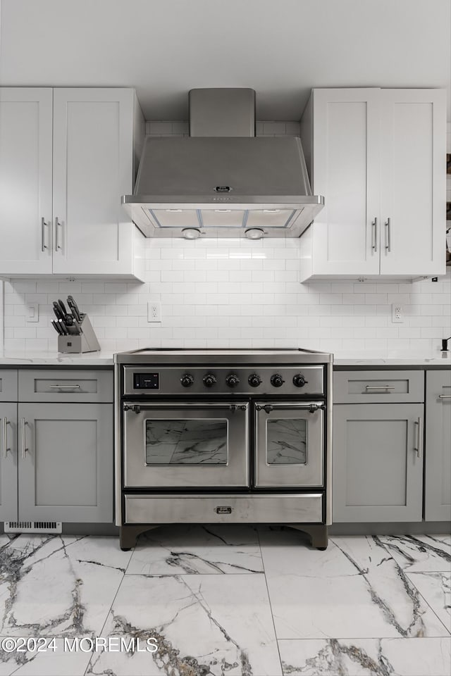 kitchen with white cabinetry, backsplash, wall chimney exhaust hood, and stainless steel range