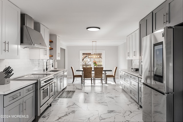 kitchen featuring tasteful backsplash, wall chimney range hood, appliances with stainless steel finishes, sink, and light stone counters