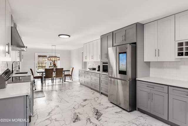 kitchen featuring stainless steel fridge, hanging light fixtures, gray cabinetry, and tasteful backsplash