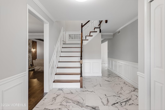 stairway with ornamental molding and wood-type flooring